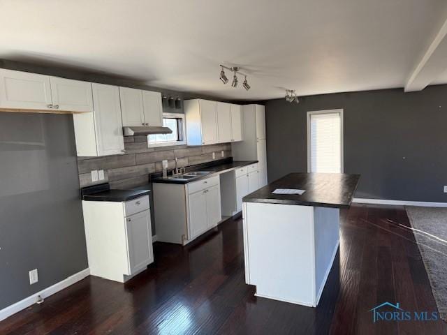 kitchen with white cabinets, dark countertops, a kitchen island, dark wood-type flooring, and under cabinet range hood