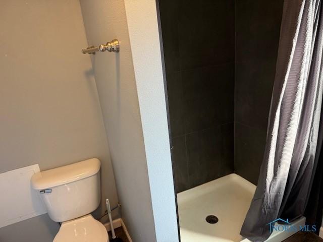 bathroom featuring a shower stall and toilet