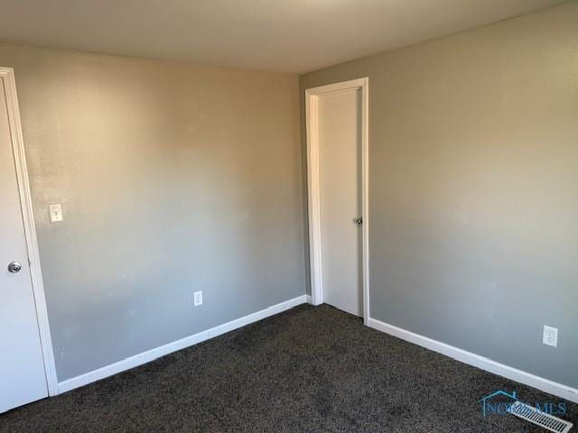 unfurnished room with dark colored carpet and baseboards