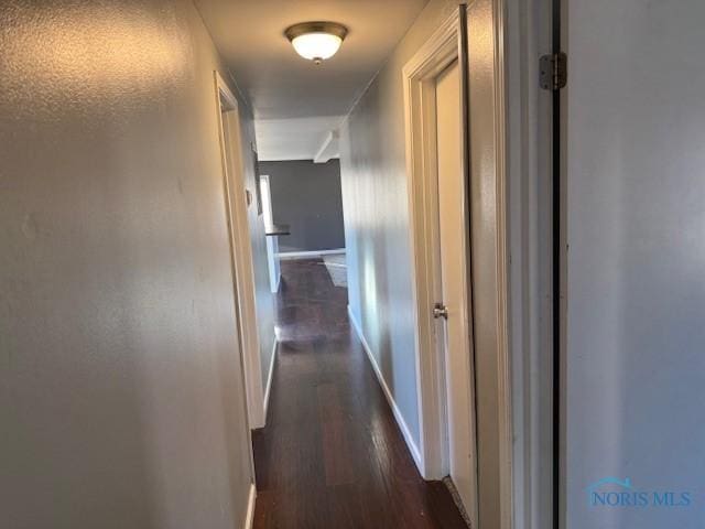 hall featuring baseboards and dark wood finished floors