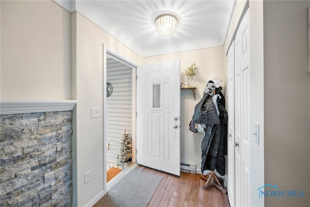 doorway with light wood-style floors, a baseboard radiator, and baseboards