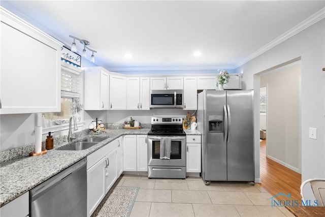 kitchen featuring appliances with stainless steel finishes, white cabinetry, a sink, and light stone countertops