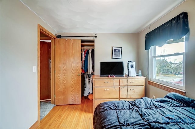 bedroom featuring light wood-style floors, a closet, and a barn door