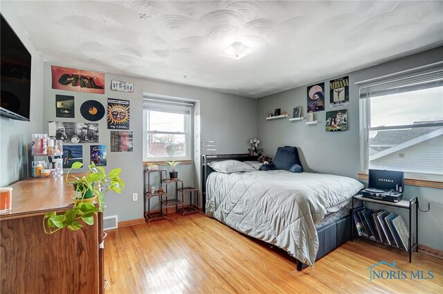 bedroom featuring baseboards, visible vents, and hardwood / wood-style floors