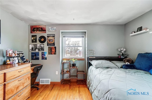 bedroom with light wood finished floors, baseboards, and visible vents