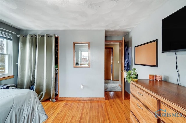 bedroom featuring baseboards and light wood finished floors