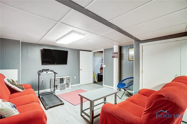 living area with a drop ceiling and wood finished floors