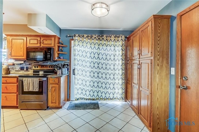 kitchen with light tile patterned floors, tasteful backsplash, stainless steel electric stove, brown cabinetry, and black microwave