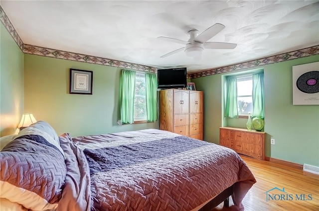 bedroom featuring light wood finished floors, multiple windows, visible vents, and baseboards