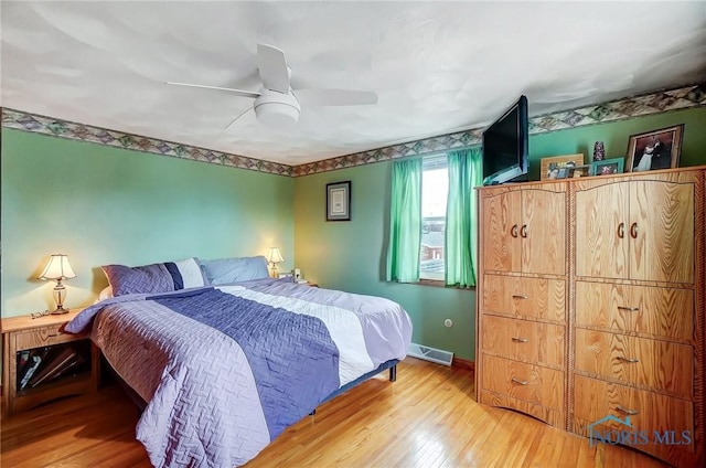 bedroom featuring visible vents, ceiling fan, baseboards, and wood finished floors