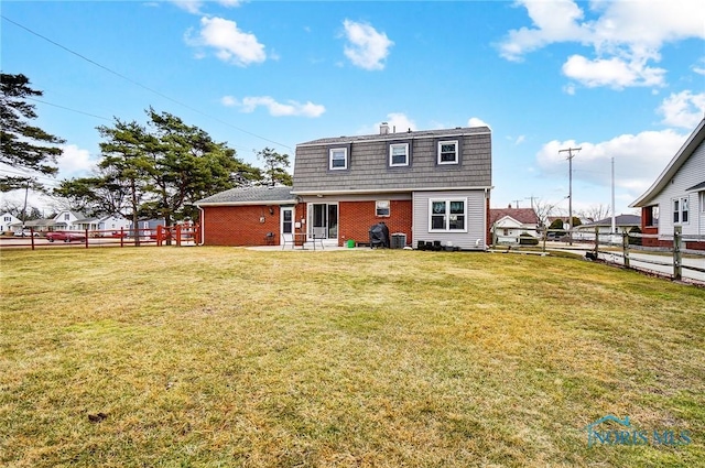 view of front of home with brick siding, a front yard, and fence