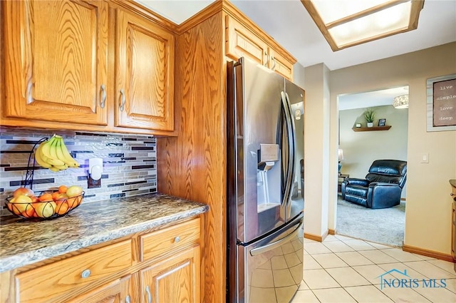 kitchen featuring tasteful backsplash, baseboards, stainless steel fridge with ice dispenser, light stone counters, and light tile patterned flooring