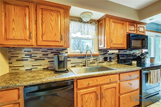 kitchen with a sink, a wealth of natural light, decorative backsplash, black appliances, and brown cabinetry