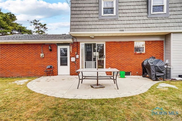 back of house with a yard, mansard roof, a patio area, and brick siding