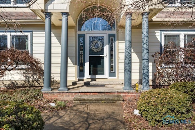 view of exterior entry with roof with shingles