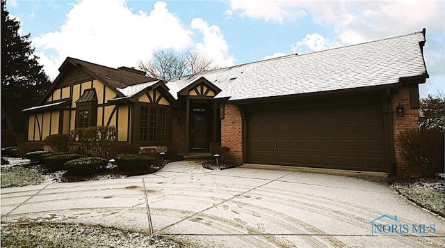 english style home with concrete driveway, brick siding, and roof with shingles