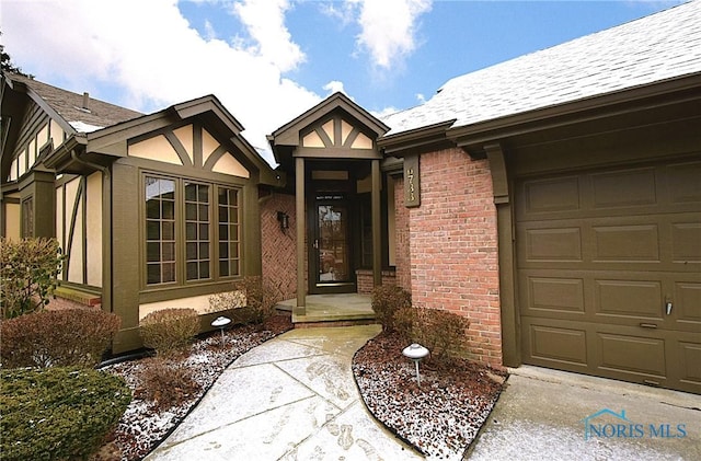 doorway to property with a garage, brick siding, and a shingled roof