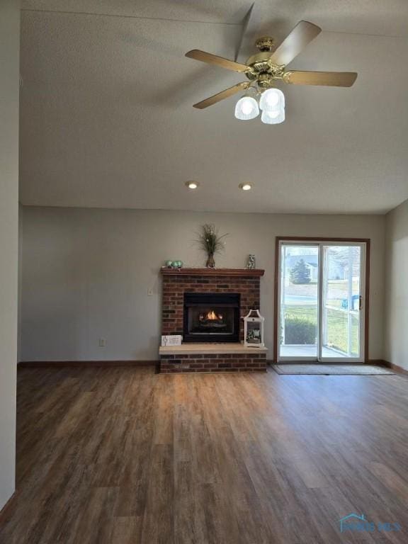 unfurnished living room featuring dark wood-style flooring, a fireplace, recessed lighting, a ceiling fan, and baseboards