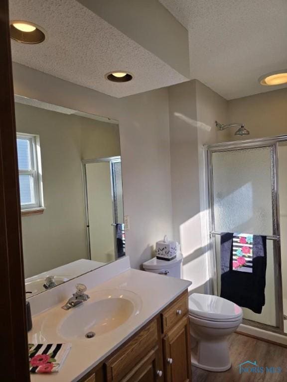 full bath with wood finished floors, toilet, vanity, a textured ceiling, and a shower stall