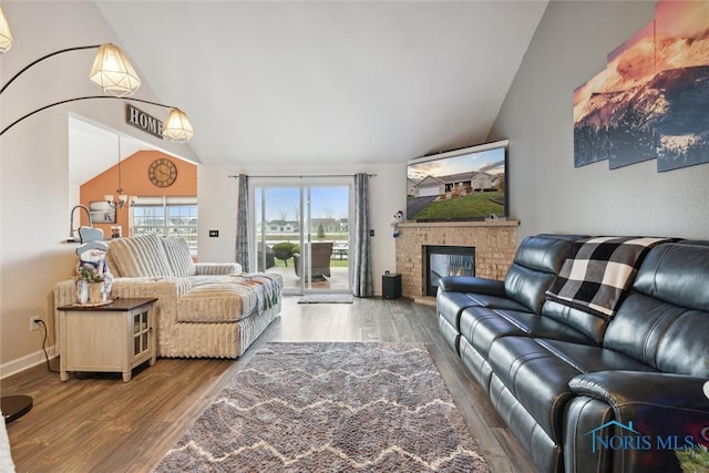 living area with high vaulted ceiling, a fireplace, baseboards, and wood finished floors