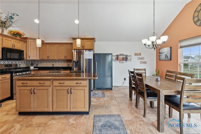 kitchen with tasteful backsplash, dark countertops, lofted ceiling, hanging light fixtures, and appliances with stainless steel finishes