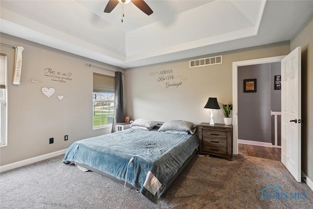 carpeted bedroom featuring ceiling fan, baseboards, visible vents, and a raised ceiling