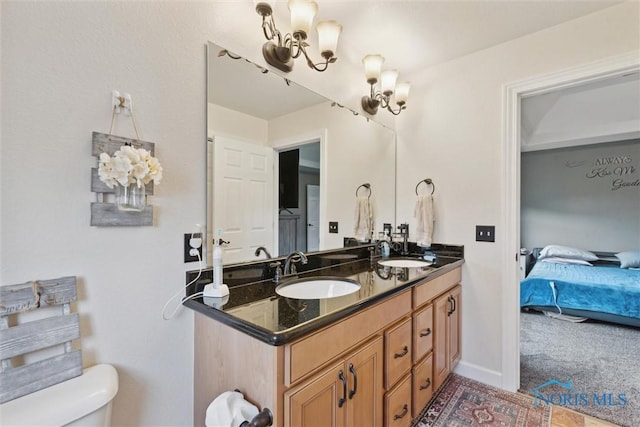 ensuite bathroom with a chandelier, connected bathroom, a sink, and double vanity