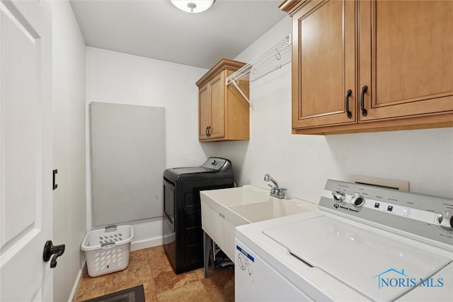 washroom featuring cabinet space, baseboards, a sink, and independent washer and dryer