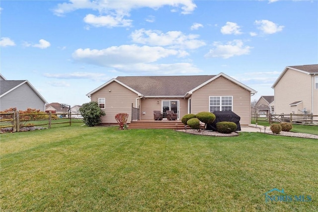 ranch-style home featuring a front yard, fence, and a wooden deck