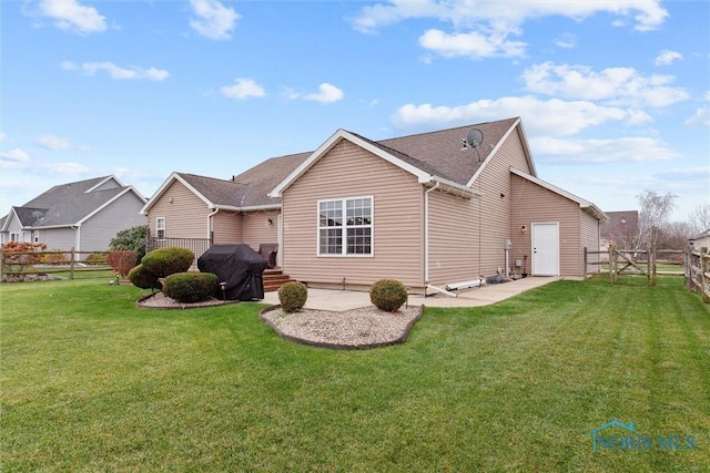 rear view of house with a fenced backyard, a patio, and a lawn