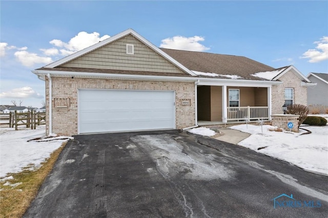 ranch-style house featuring aphalt driveway, covered porch, and an attached garage