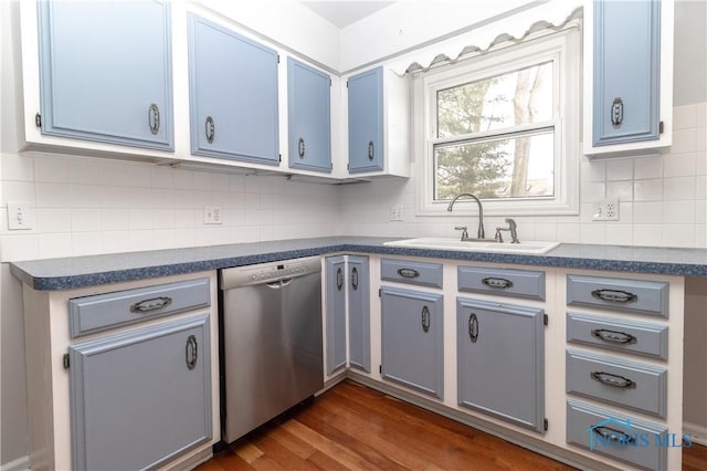 kitchen with a sink, stainless steel dishwasher, dark wood-style floors, tasteful backsplash, and dark countertops