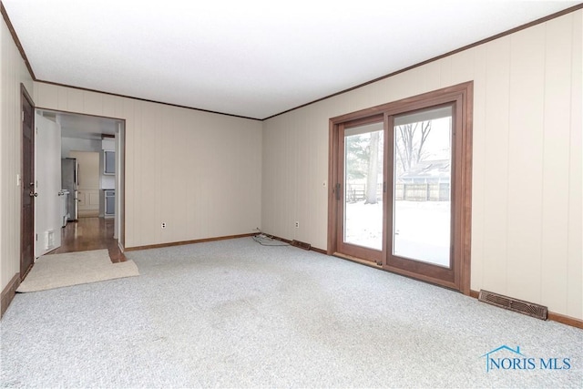 spare room featuring crown molding, baseboards, visible vents, and light colored carpet