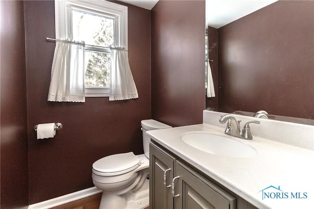 bathroom featuring baseboards, vanity, and toilet