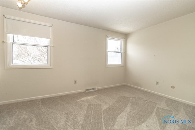 carpeted spare room featuring visible vents and baseboards