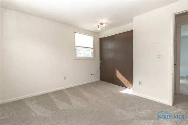 unfurnished bedroom with a closet, carpet flooring, and baseboards