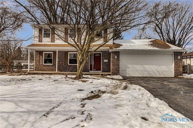 traditional home featuring a garage, brick siding, and aphalt driveway