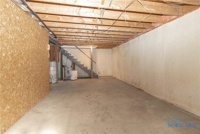 unfinished basement featuring gas water heater and stairs