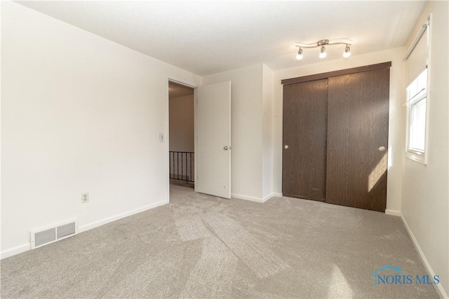 unfurnished bedroom featuring light carpet, baseboards, visible vents, and a closet