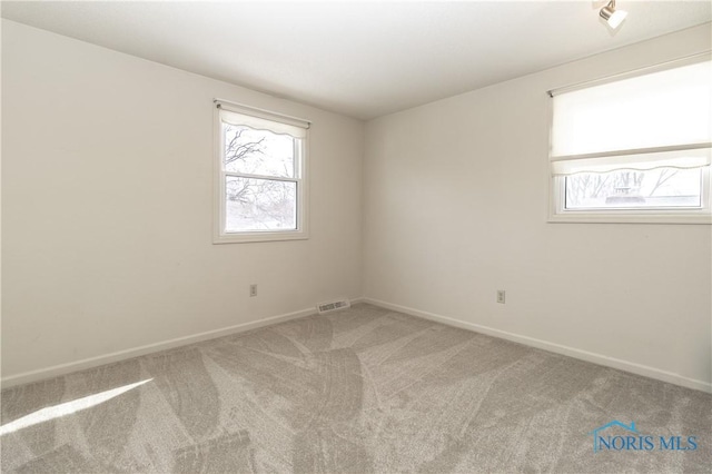 unfurnished room featuring carpet, visible vents, and baseboards