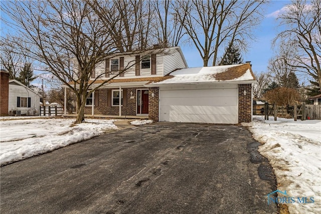 traditional-style home with a garage, brick siding, driveway, and fence