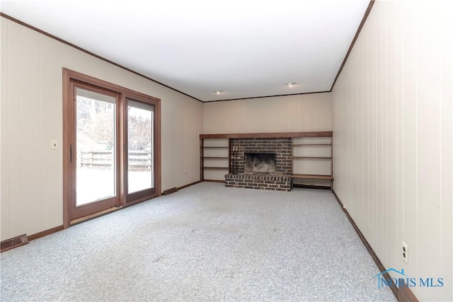 unfurnished living room featuring light colored carpet, a brick fireplace, visible vents, and crown molding