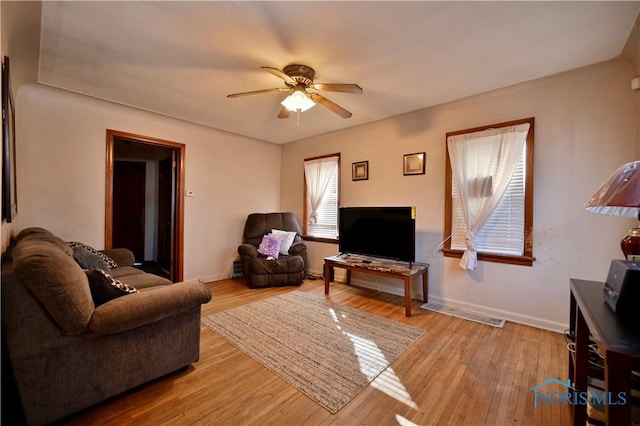 living room with light wood finished floors, baseboards, and a ceiling fan