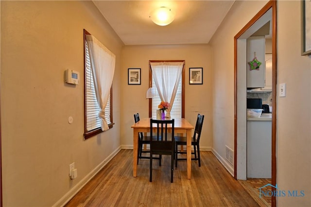 dining room featuring visible vents, baseboards, and wood finished floors