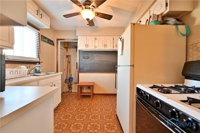 kitchen with light countertops, light floors, white gas stove, and white cabinets