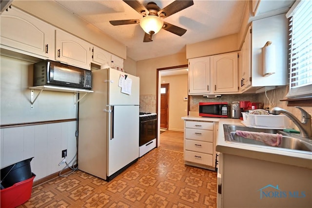 kitchen with white appliances, a sink, white cabinets, light countertops, and light floors