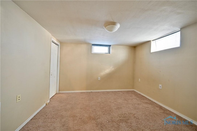 below grade area featuring a textured ceiling, baseboards, and carpet flooring