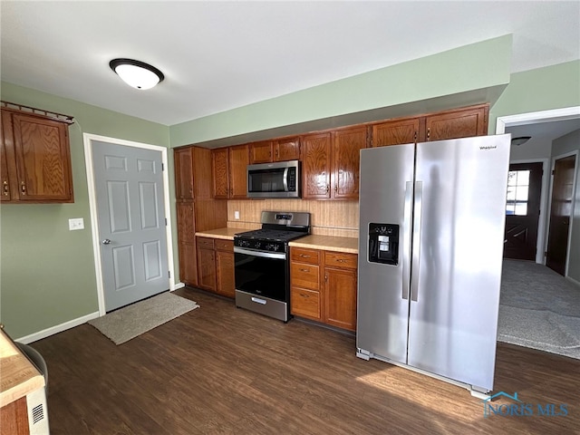 kitchen with dark wood-style floors, brown cabinets, stainless steel appliances, light countertops, and backsplash