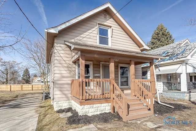 bungalow-style house featuring covered porch and fence