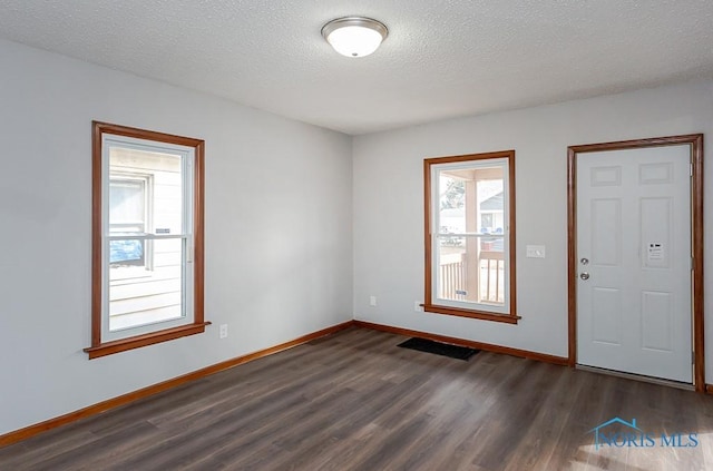 interior space with visible vents, baseboards, dark wood finished floors, and a textured ceiling